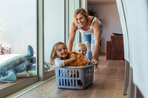 Mother playing with her children in laundry basket