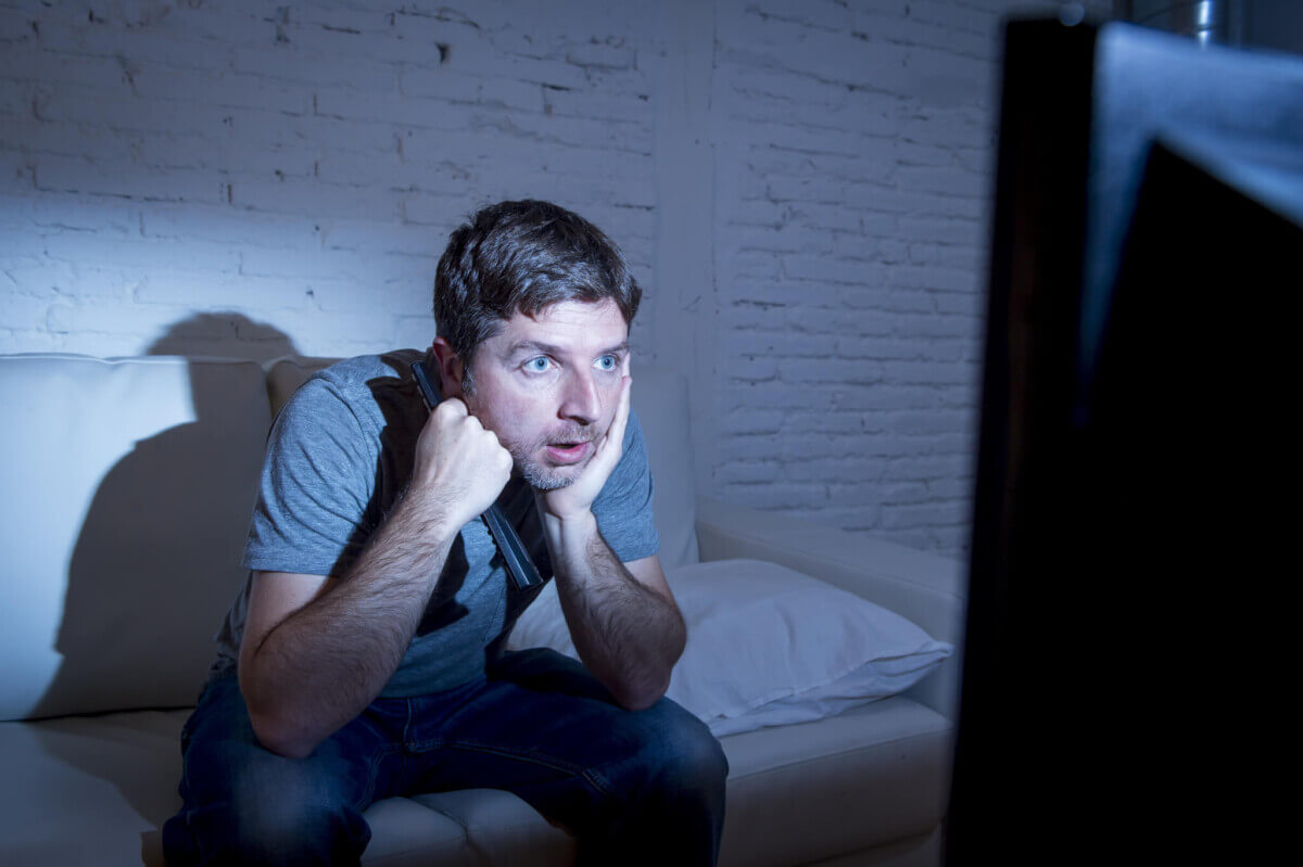 Man sitting on couch watching TV