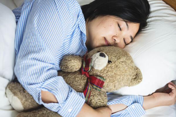 A woman sleeping in bed with a teddy bear