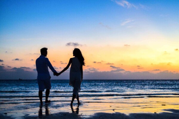 Couple walking along the beach at sunset