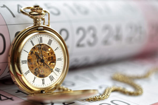 Time: Gold pocket watch on top of calendar
