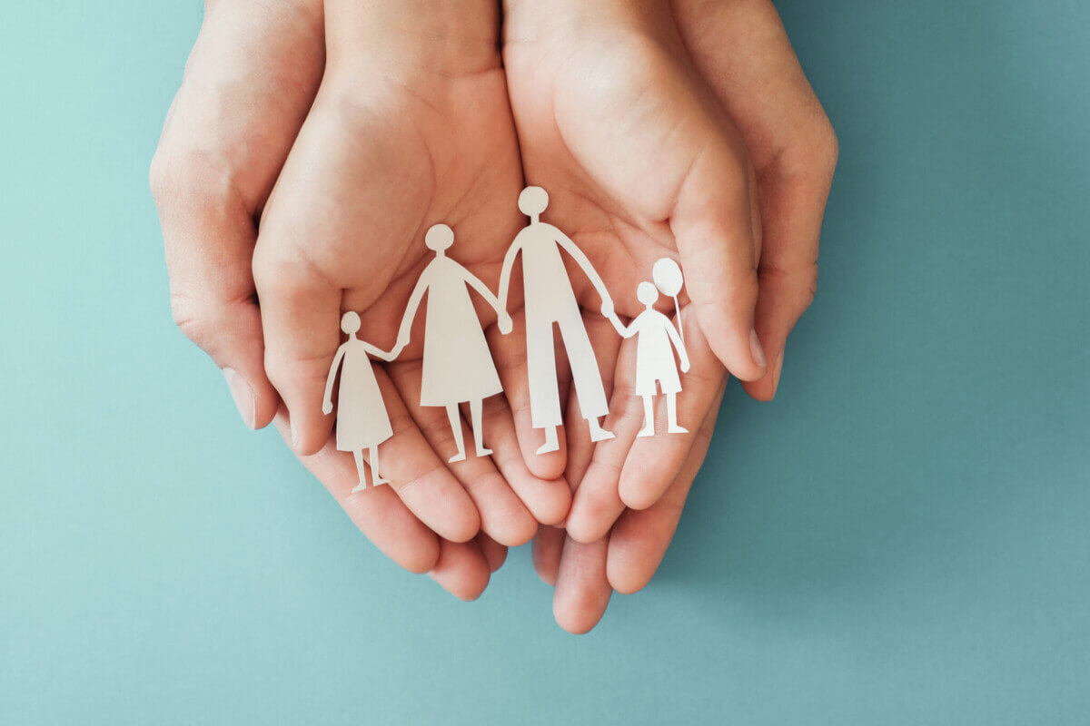 hands holding paper family cutout, family home, adoption foster care, homeless charity ,family mental health, international day of families, Autism support, domestic violence,social distancing concept