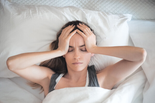 Tired, stressed woman with headache sleeping in bed