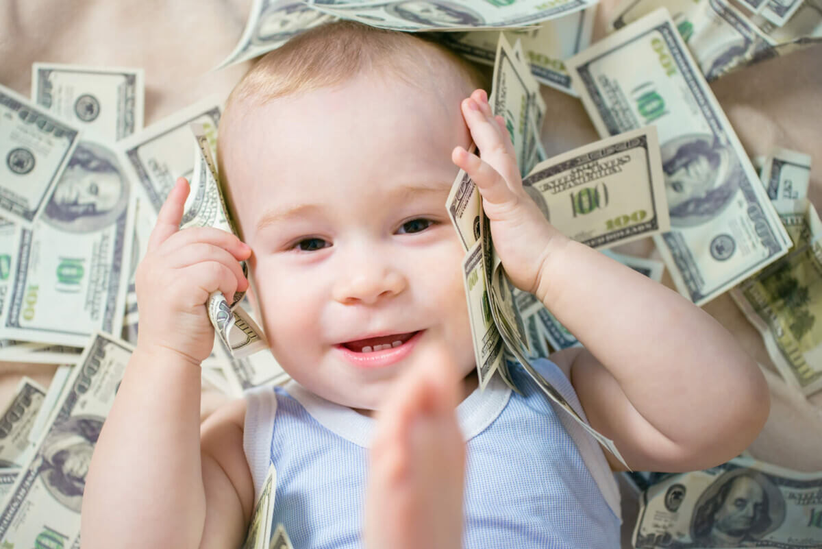 Cute hapy baby boy playing with a lot of money, american hundred dollars cash