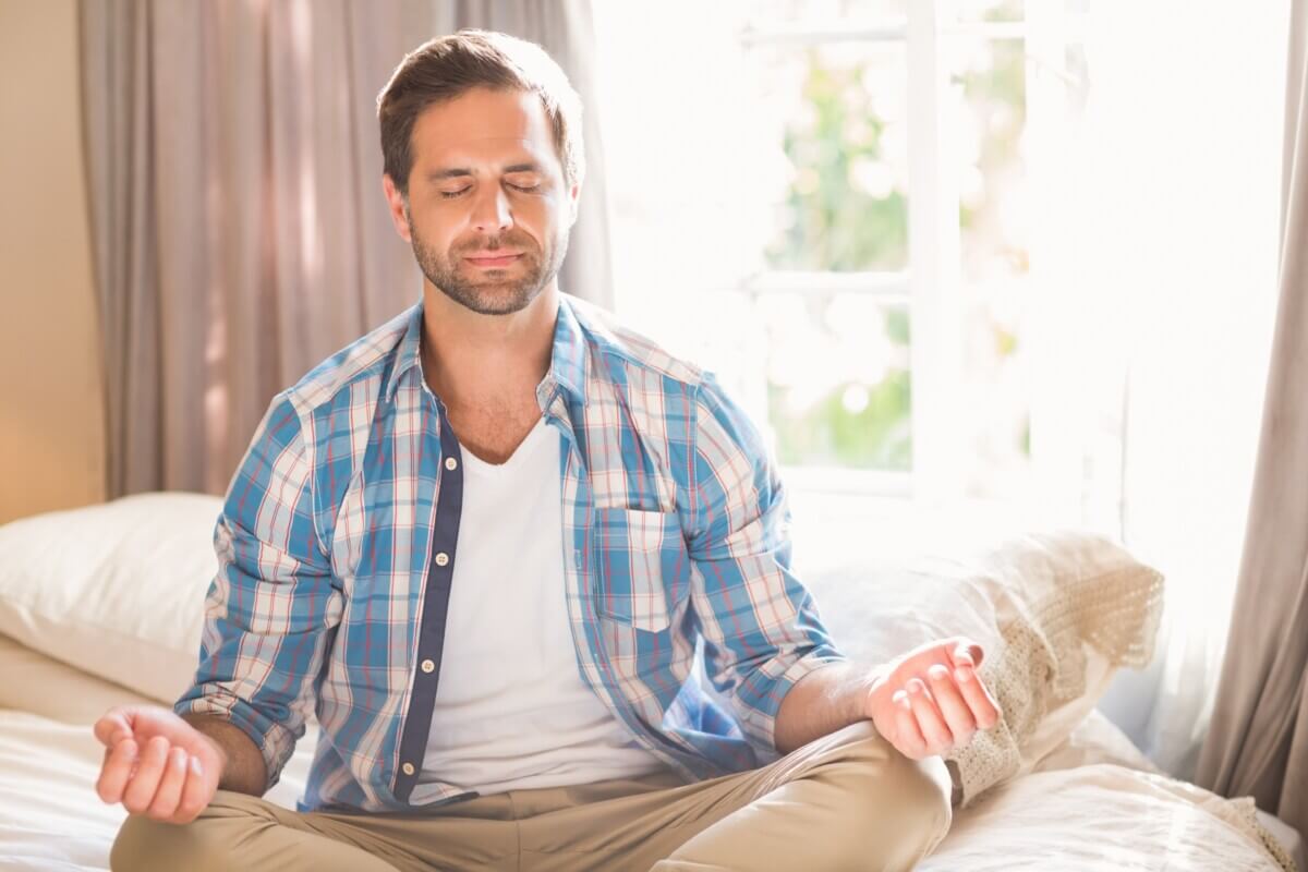 Man practicing mindfulness meditation on bed