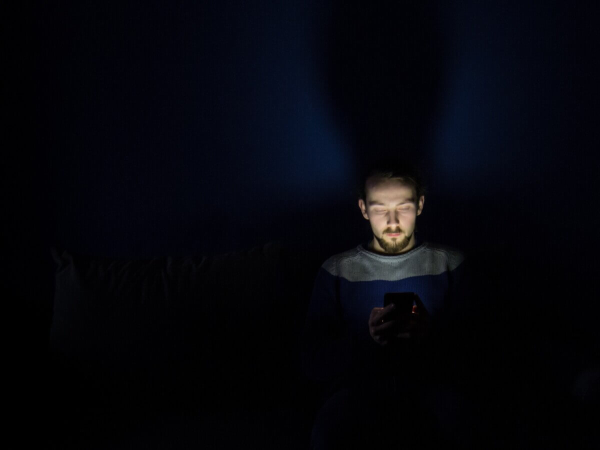 Man looking at smartphone in bed at night