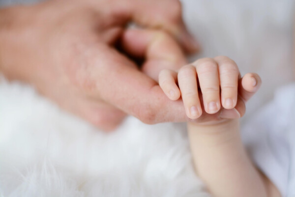 Baby's hand holding father's finger