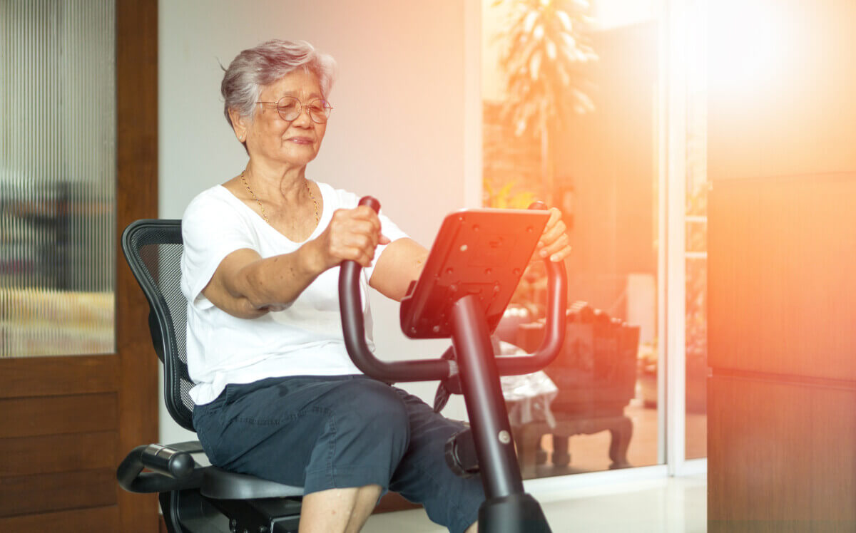 Older, elderly woman working out on stationary exercise bike