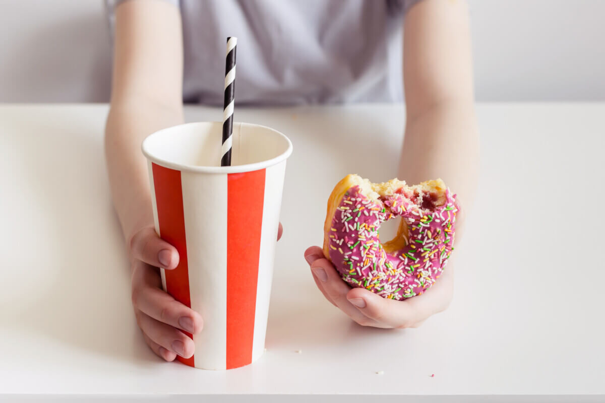 Junk food: Teen boy holding donut and sweet fizzy drink