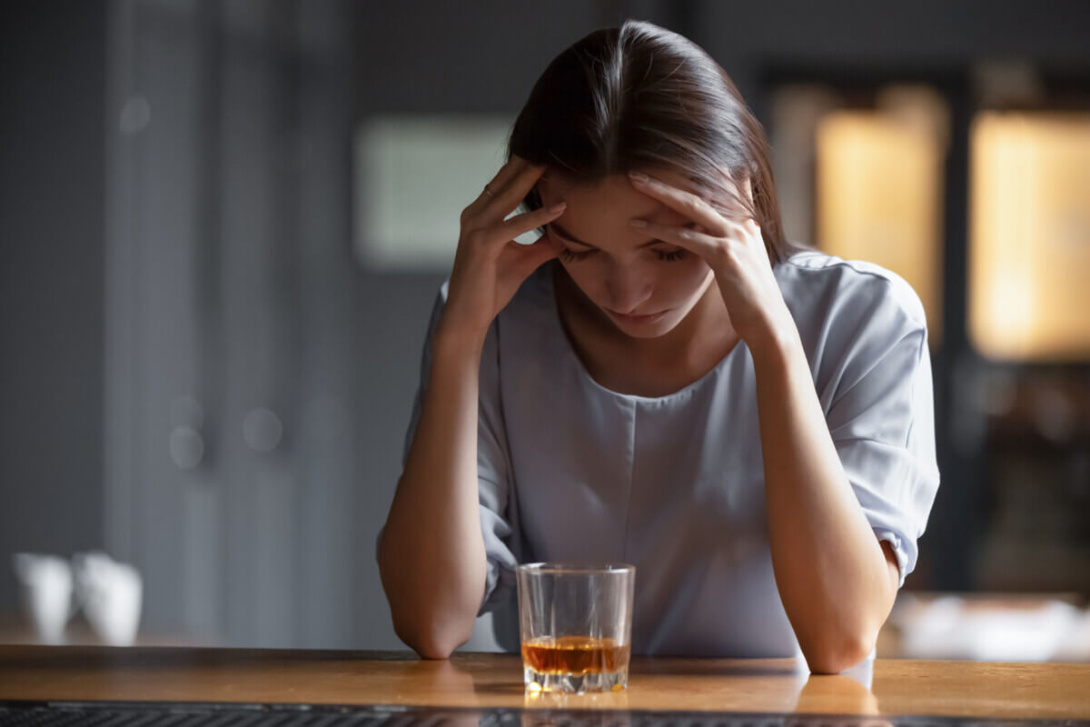 Depressed sad young addicted woman feeling bad drinking whiskey alone