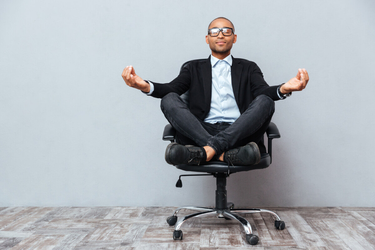 Man practicing mindfulness meditation or yoga on office chair