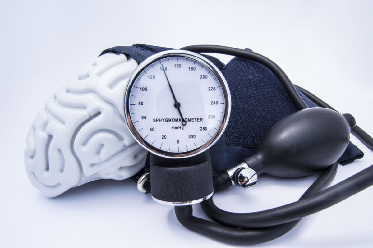 The figure of the human brain enveloped sphygmomanometer cuff with bulb (pear) and dial showing high blood pressure. Concept high brain or increased (raised) intracranial pressure (hypertension)