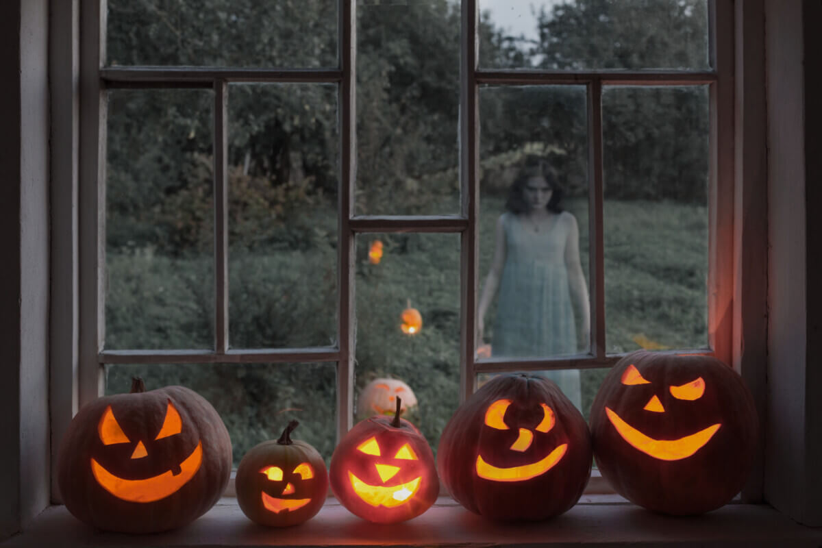 Halloween pumpkins on windowsill with ghost outside  window