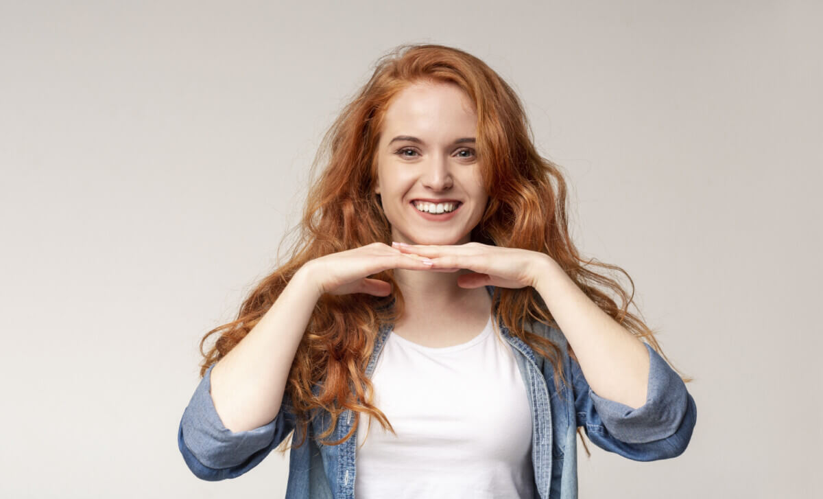 Portrait of happy redhead girl leaning chin on her palms