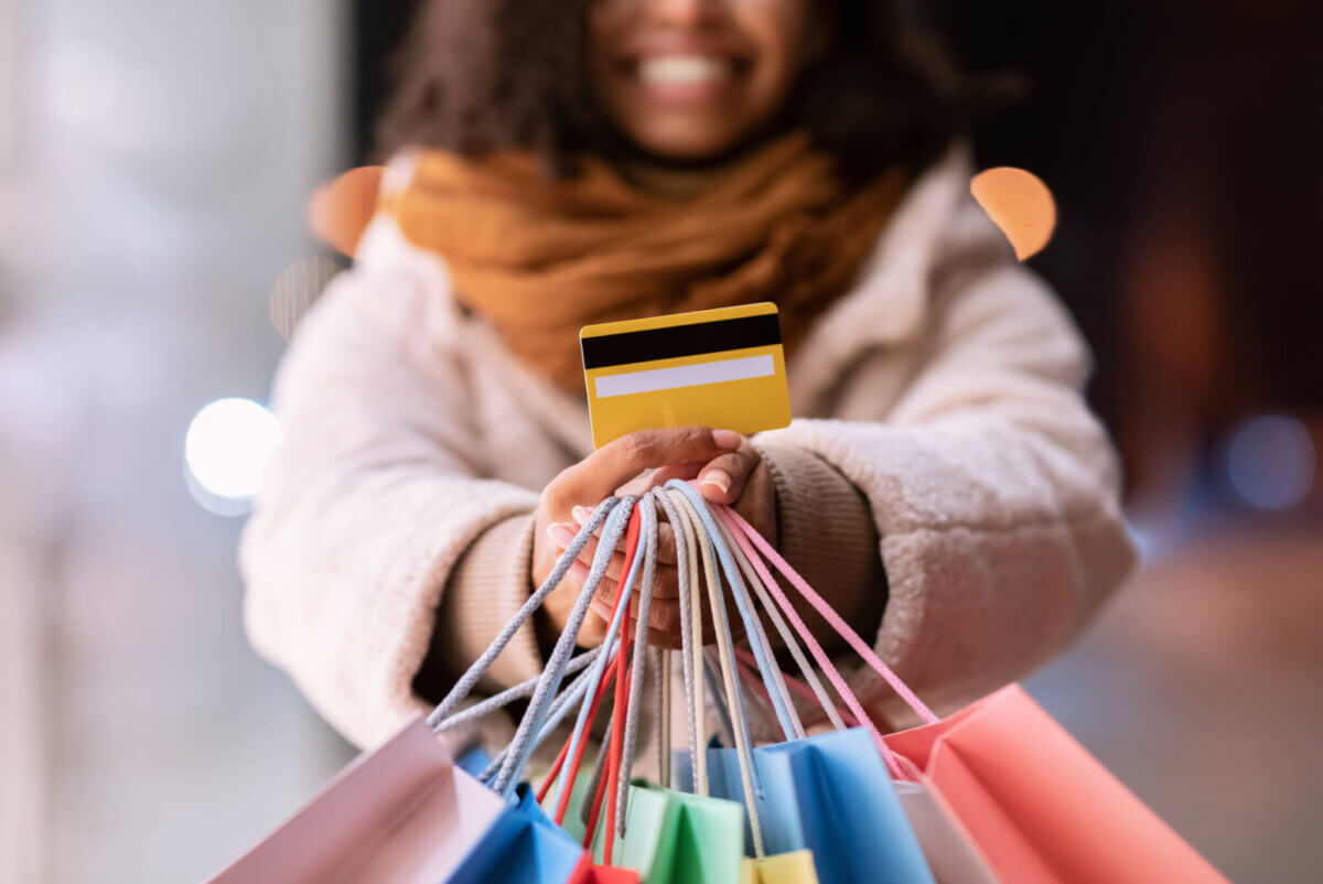 Woman showing credit card and shopping bags