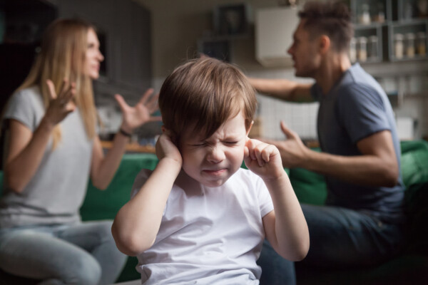 Parents fighting, arguing while scared child puts fingers in ears