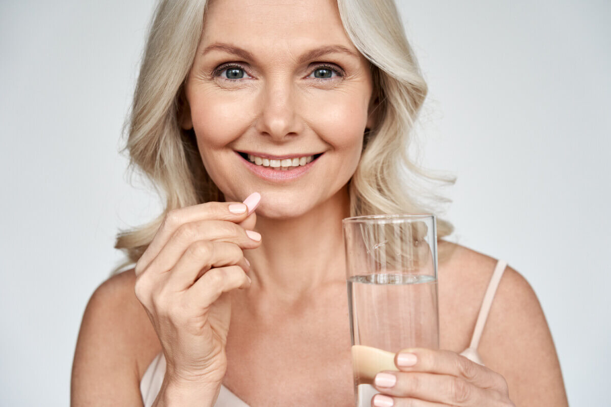 Woman holding vitamin or multivitamin pill
