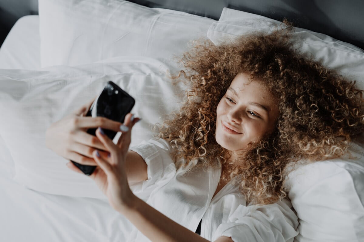 Woman taking selfie in bed