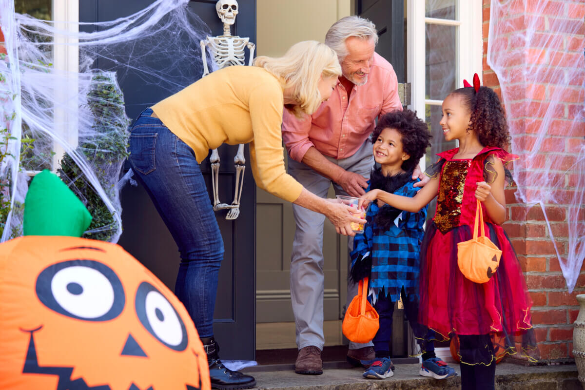 Older couple giving children Halloween candy