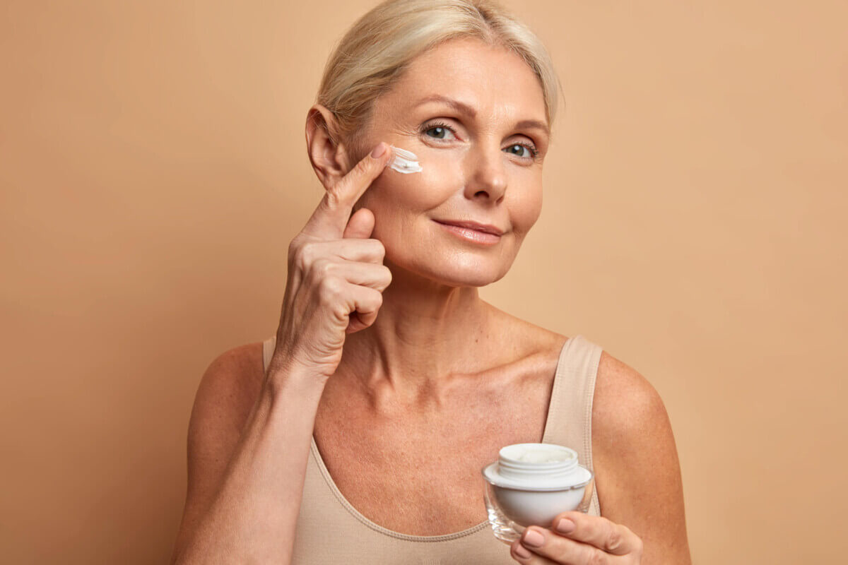 Woman applying anti-aging cream to wrinkles on her face