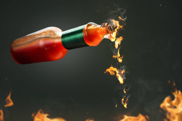 Hot sauce with fire droplets coming from bottle for spicy food