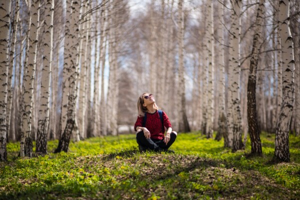 Woman sitting outside in forest, enjoying nature outdoors.