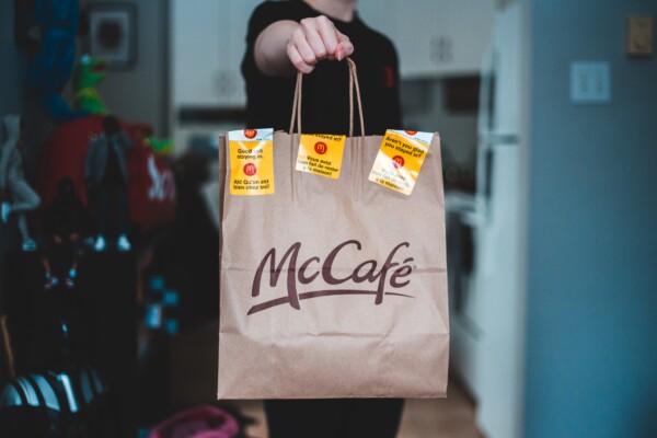 McDonald's worker holding a McCafe breakfast bag
