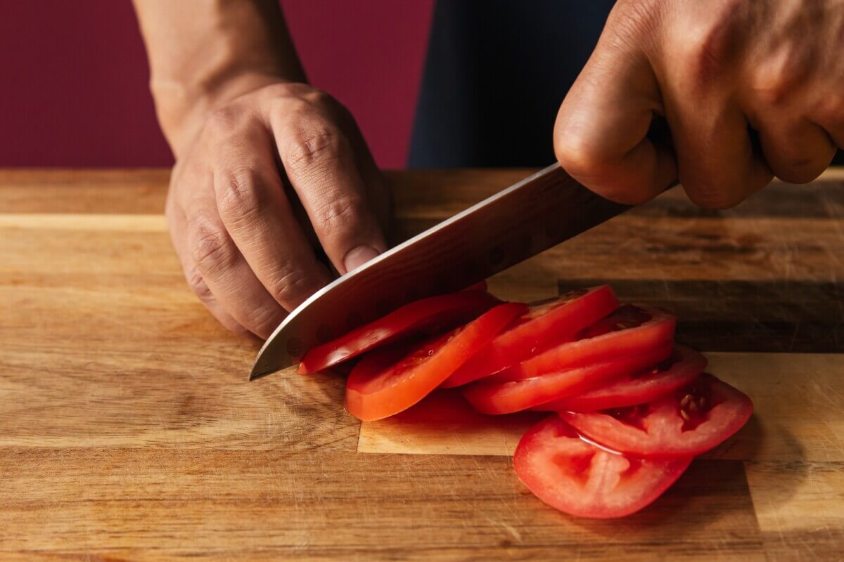 Chef using knife to slice tomato
