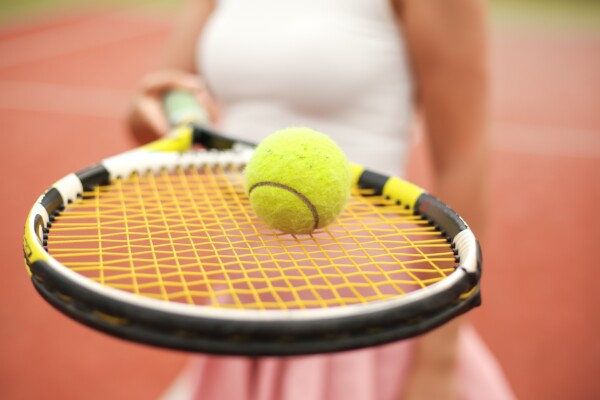 Woman holding tennis racket with ball on top