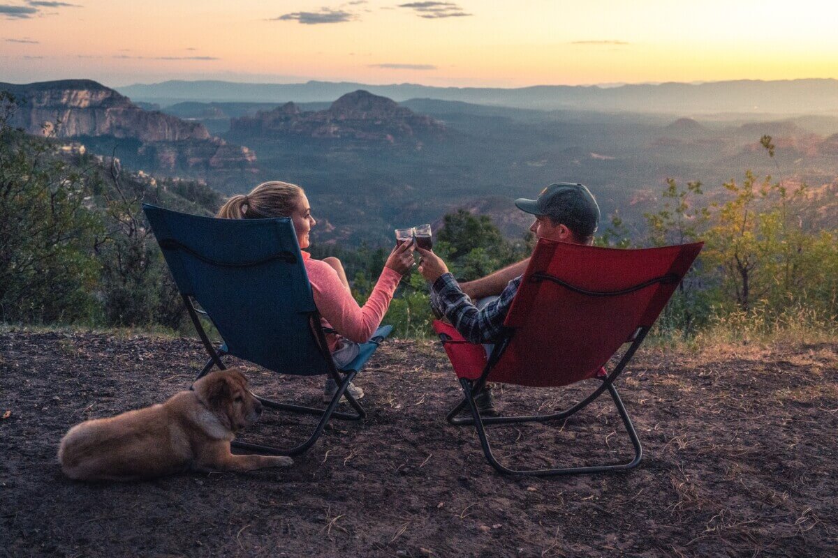 Couple toasting to the great outdoors while lounging in their camping chairs