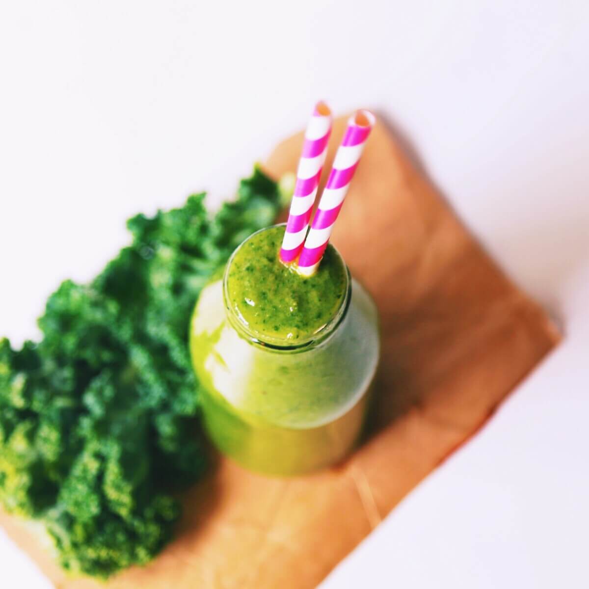 Delicious green smoothie in a bottle with straws