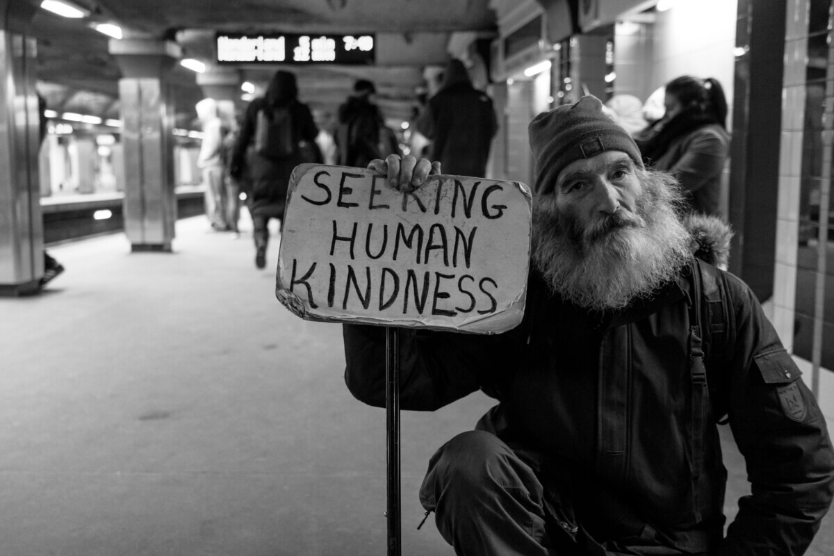 Homeless man holds sign asking for human kindness