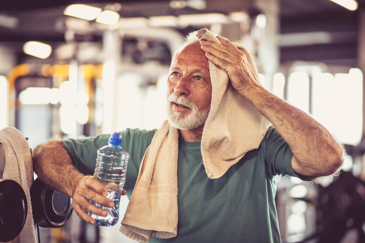 Older man wiping off the sweat from an intense exercise routine at the gym
