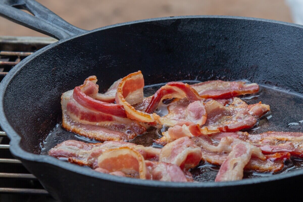 Sizzling bacon being cookied in a skillet