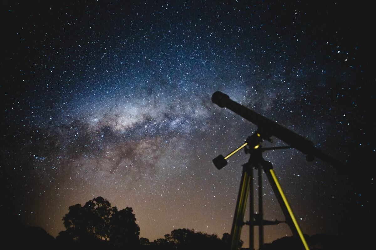 Telescope looking out at stars and planets in spectacular night sky