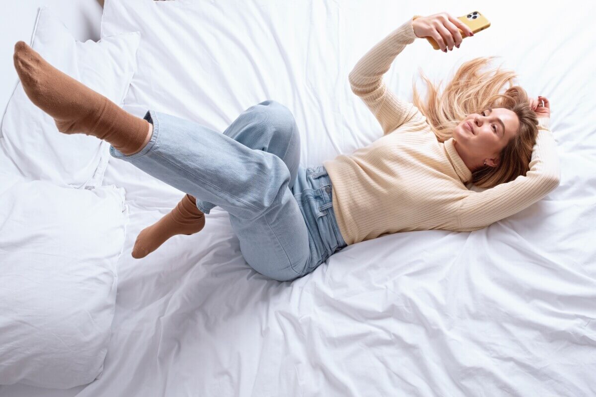 Woman in denim jeans lying down taking selfie