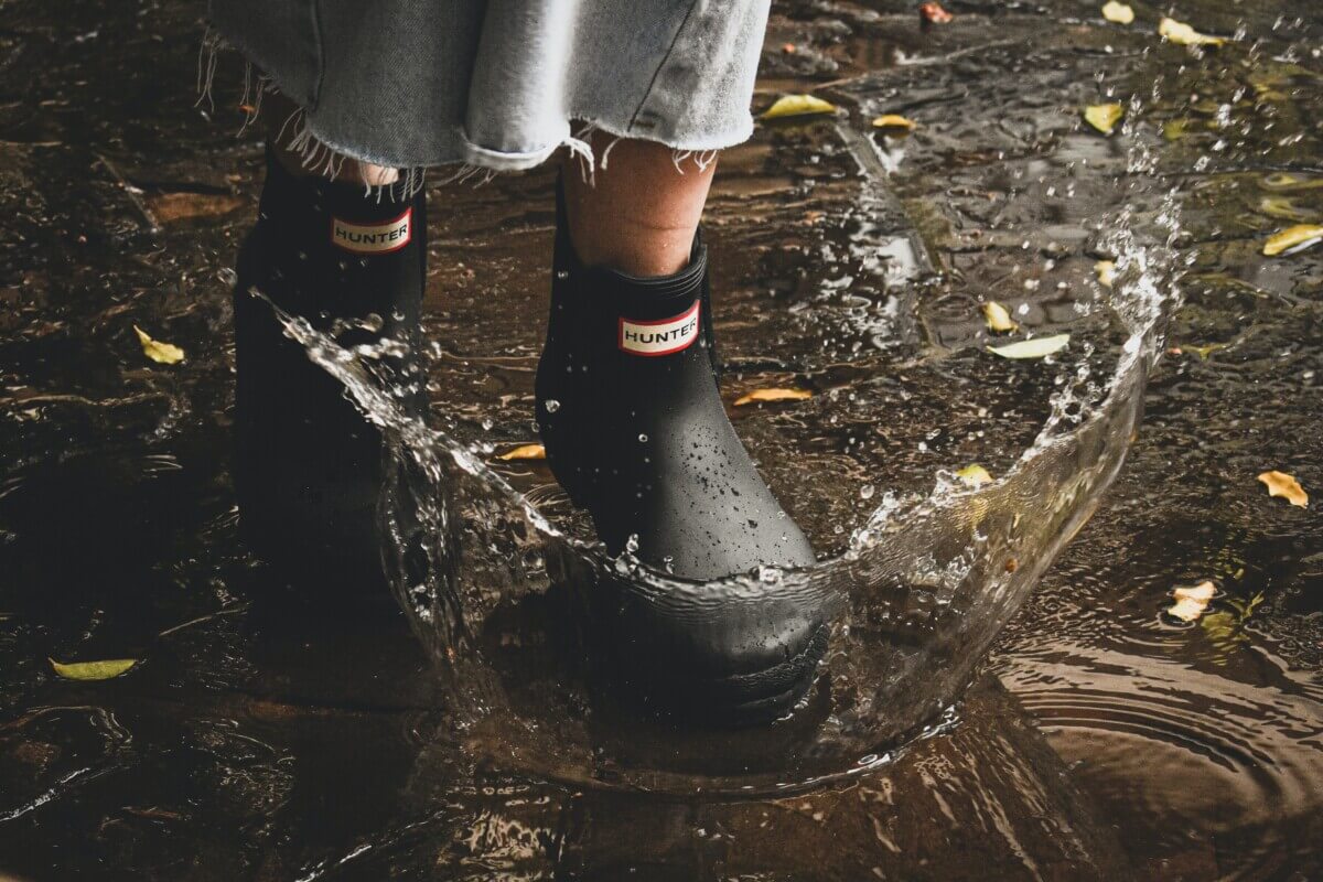 Woman walking through puddle in Hunter rain boots