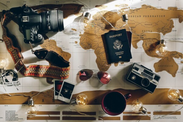 a passport, camera, glasses, mug, photos laying on a map