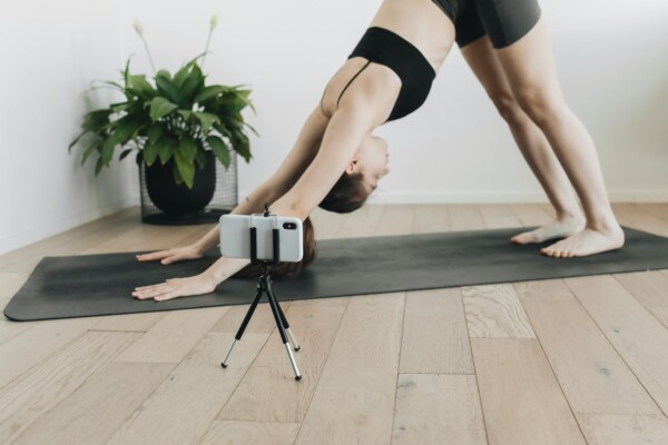 a girl doing yoga with her phone on a tripod