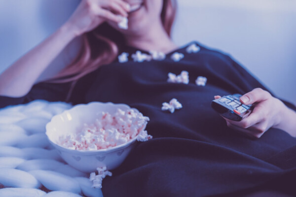 image of woman eating a bowl of microwave popcorn on the couch