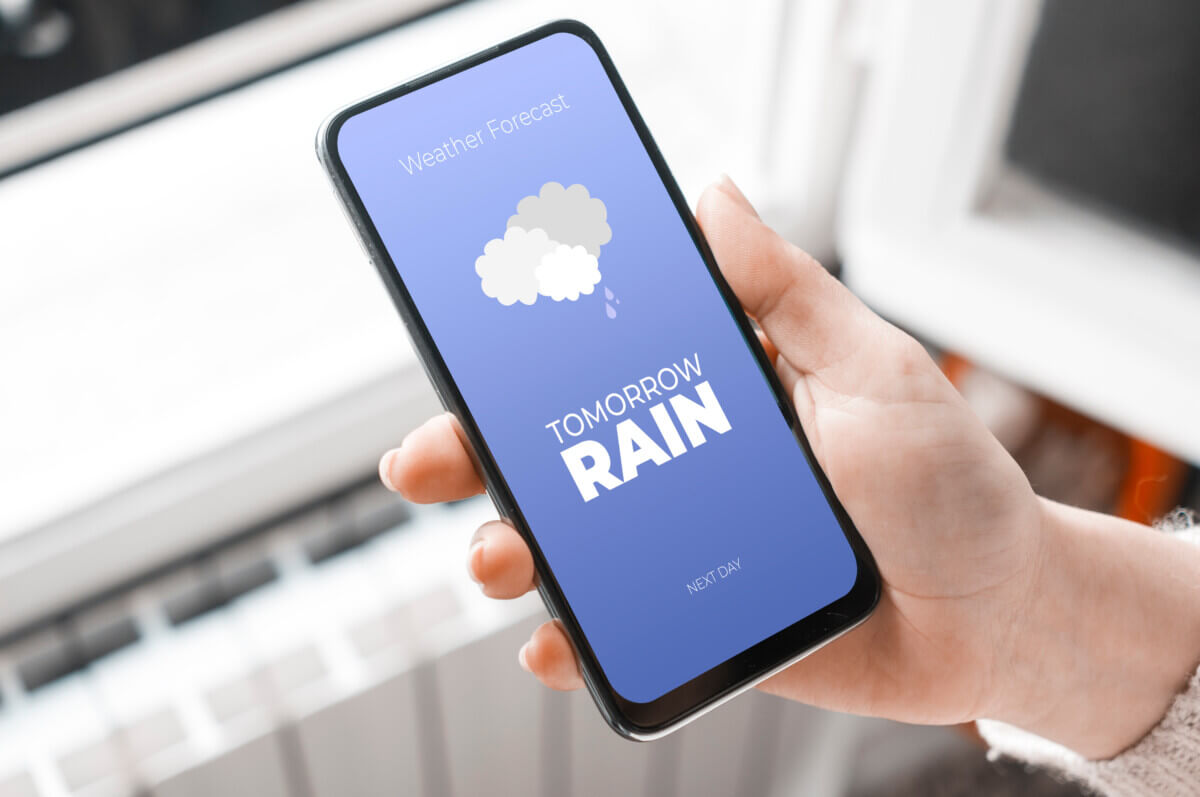 Woman checking weather app on smartphone, showing rain tomorrow