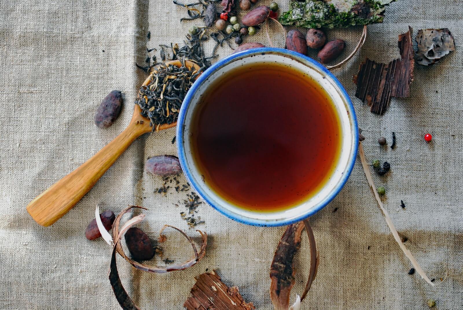 A cup of tea surrounded by herbs