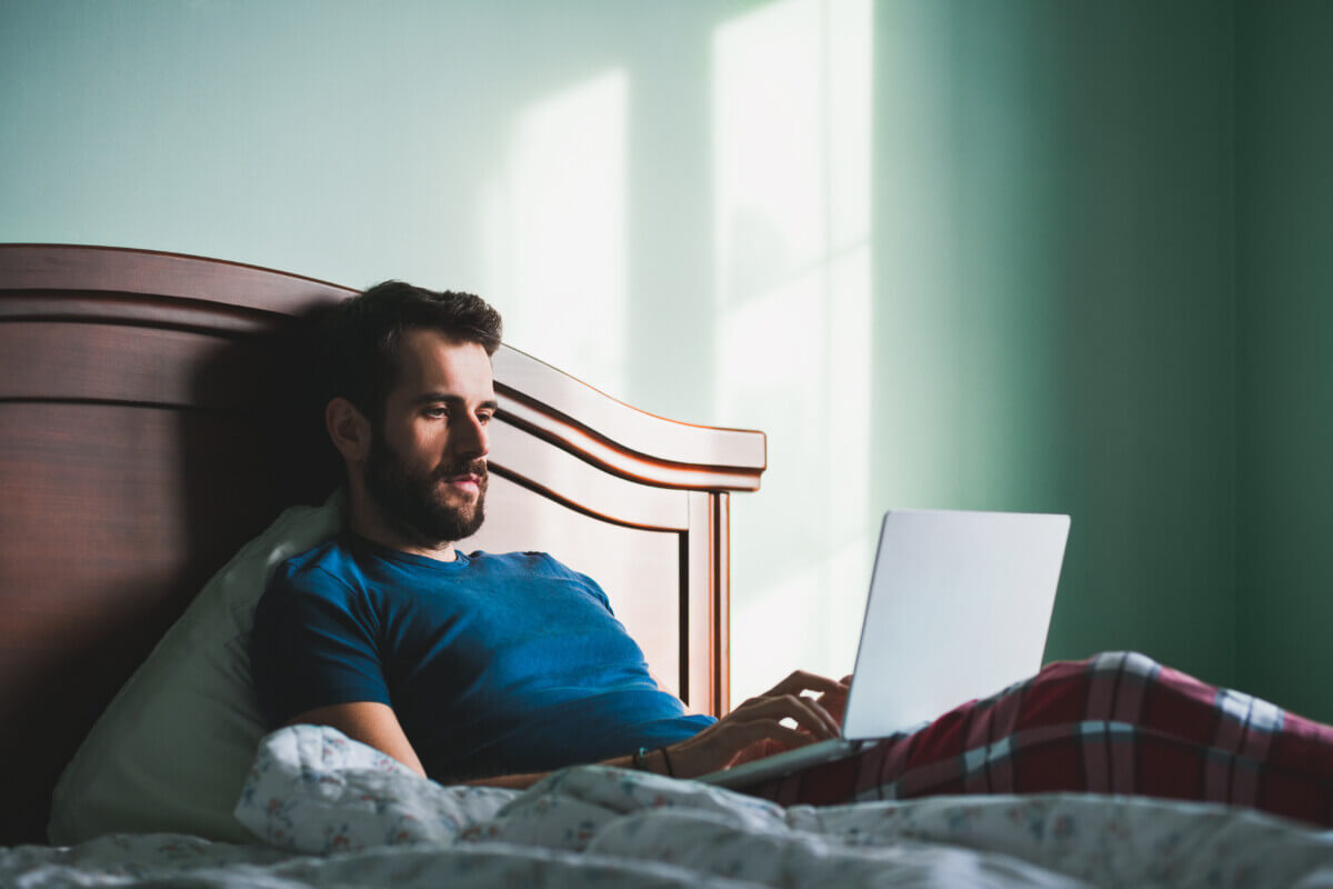 Man working on laptop computer in bed