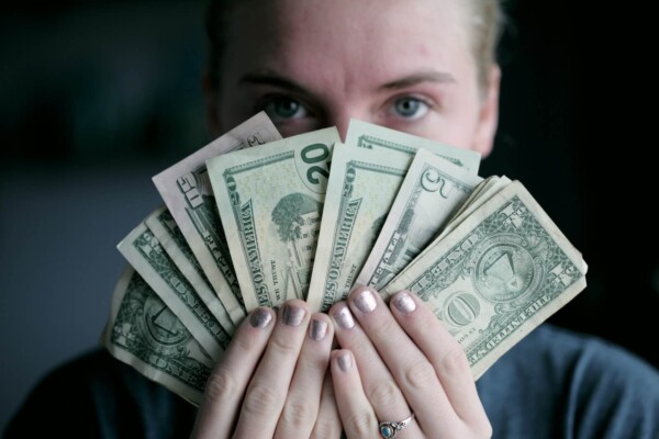 Person hides face with cash