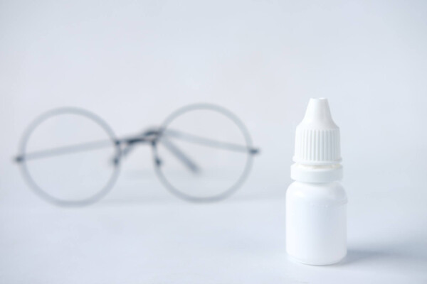 white eye drop bottle and glasses