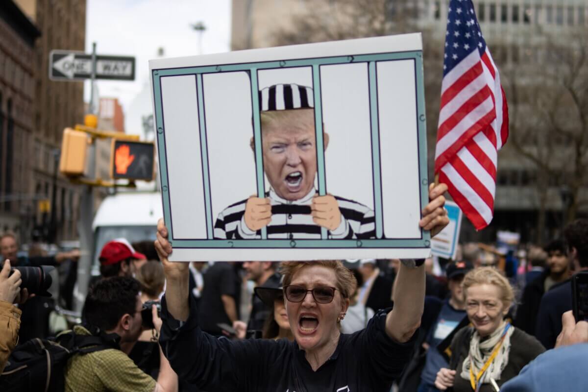 Protester holds sign depicting Donald Trump in prison