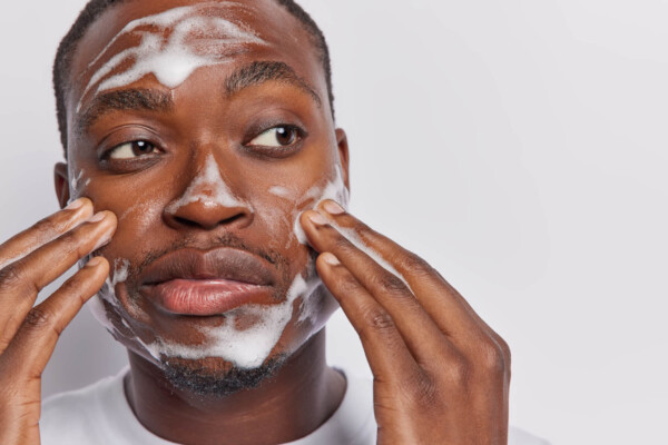 Black man cleansing and washing his face with soap