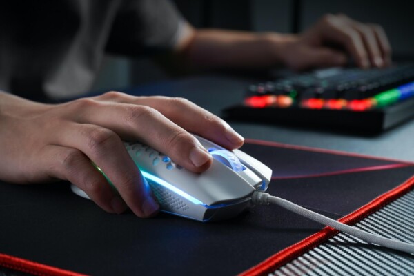 person holding black and gray mouse with RGB keyboard and mousepad