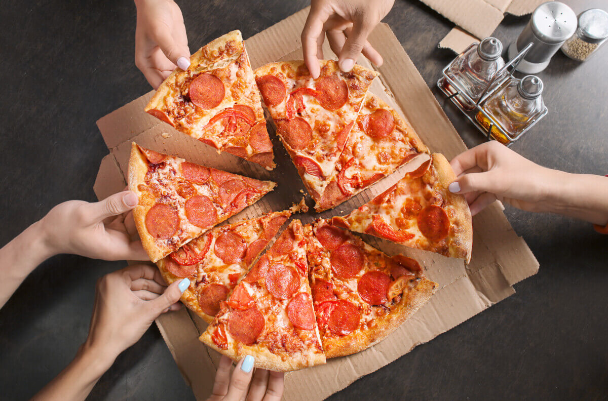 A group of people grabbing pizza slices