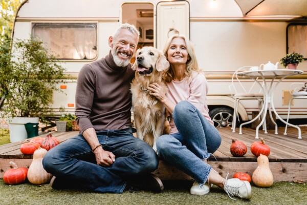 A happy older couple and their dog outside of an RV
